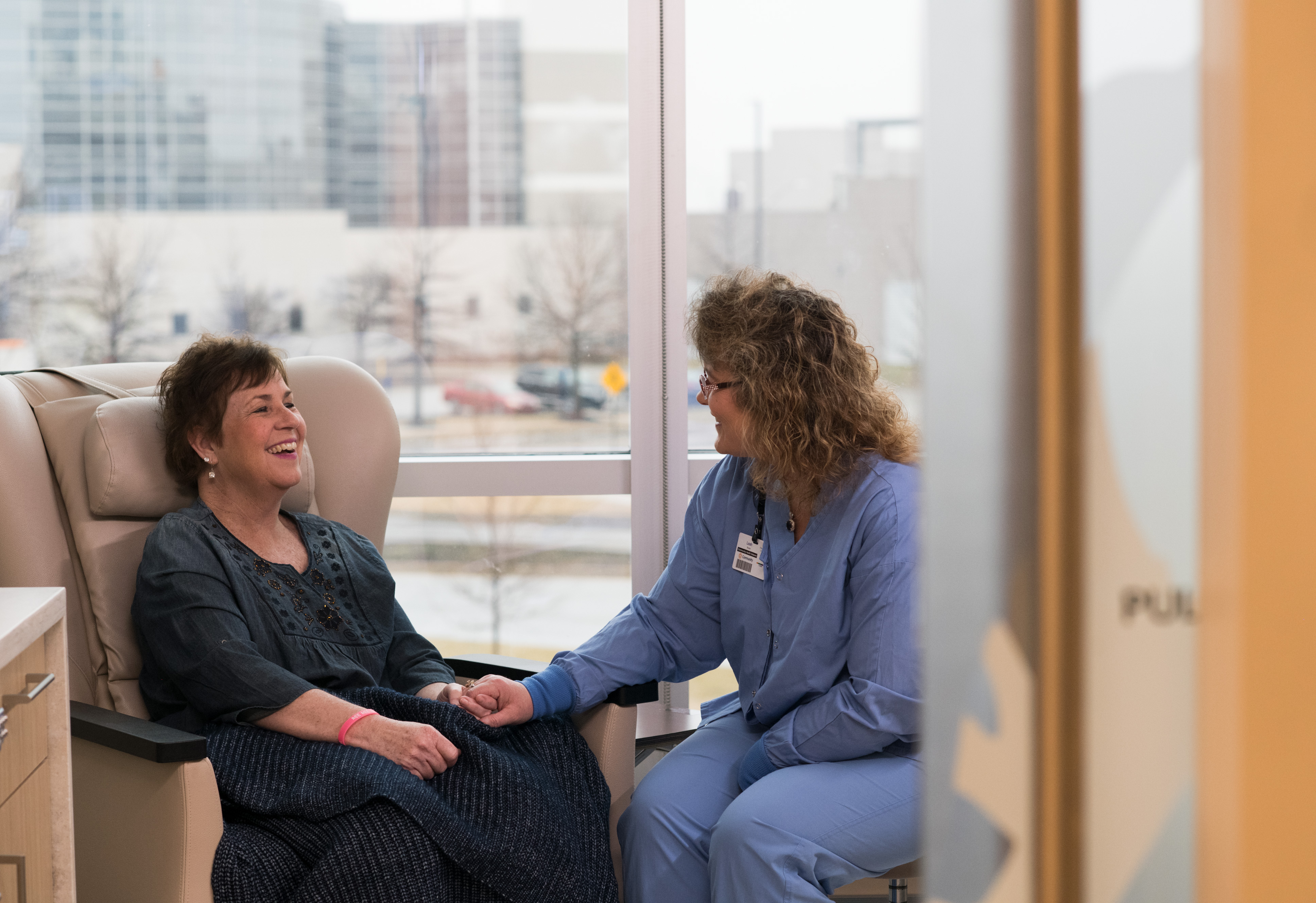 Nurse comforts a patient, who smiles.
